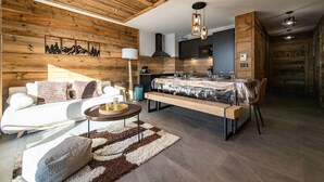A modern kitchen with wooden accents, a dining area with a bench, and a living space with a sofa and a coffee table. - Apartment for 6/8 people with jacuzzi in a new residence on the slopes (LA TOUSSUIRE)