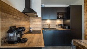 A modern kitchen with dark cabinetry, a wooden countertop, a coffee machine, and a microwave. - Apartment for 6/8 people with jacuzzi in a new residence on the slopes (LA TOUSSUIRE)