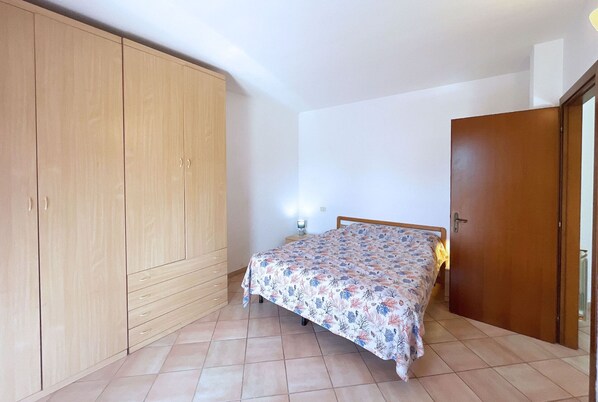 Un dormitorio con cama, armario y mesita de noche.