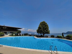 Una piscina con vista chiara sul mare e sulle montagne sullo sfondo.