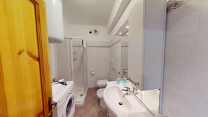Un bagno dotato di lavatrice, toilette, lavandino e zona doccia.