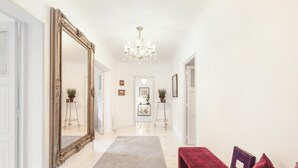 A hallway with a large ornate mirror, a chandelier, and a red bench with a book. - 3 Bedroom Apartment in Heart of Cannes (Cannes)
