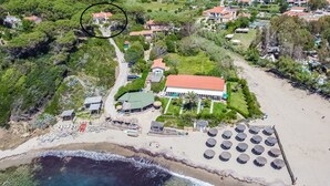 Luftaufnahme eines Küstenresorts mit einem großen Gebäude, Strandstühlen und einem Sandstrand.