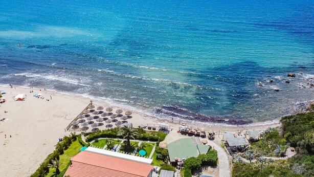 Ein Strandhotel mit Pool, Sonnenschirmen und Blick auf den Ozean.