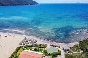 A beach resort with a pool, umbrellas, and a view of the ocean. - Villa Scirocco Ovest - Villa Scirocco Ovest (Capoliveri)