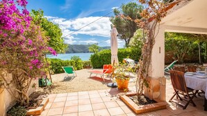 Eine Terrasse mit Meerblick, Sitzgelegenheiten im Freien und Topfpflanzen.