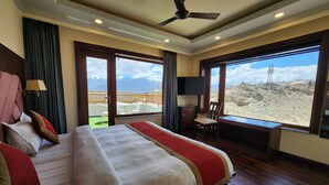Camera d'albergo con un letto grande, una scrivania, una sedia e vista su un paesaggio desertico dalle finestre.