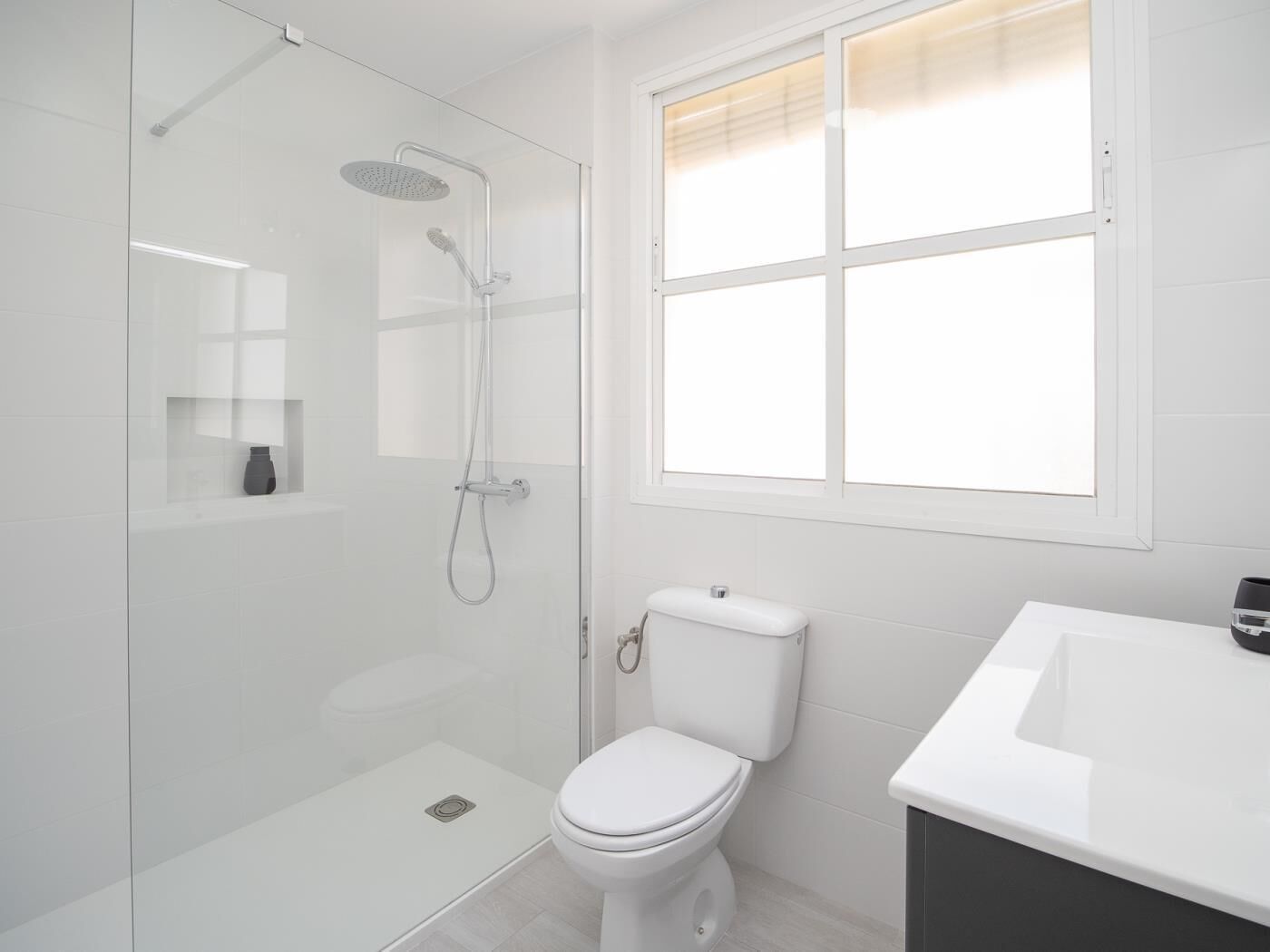 Un baño moderno con ducha de vidrio, inodoro blanco y lavabo.