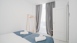 A modern hotel room with a large bed, a wooden swing chair, and a wardrobe.