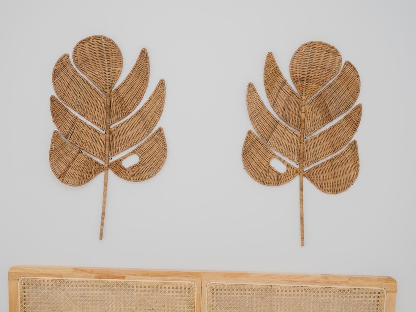 Deux feuilles tissées fixées au mur et un panneau en bois orné d’un motif tissé.