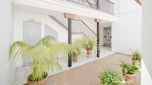 A spacious indoor area with a staircase, potted plants, and a tiled floor.
