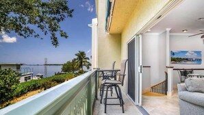 A balcony with a view of the sea, a dining area with chairs, and a sofa. - Serenity Retreat- 2/2 Townhouse, Dock & Pool (Key West)