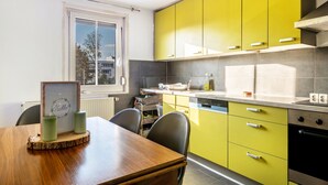 A kitchen with yellow cabinets, a wooden dining table, and a framed picture on the table. - Holiday Apartment 'Ludwigsburg' with Wi-Fi (Ludwigsburg)
