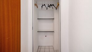 Un placard avec des portes en bois, un intérieur blanc et un sol carrelé.