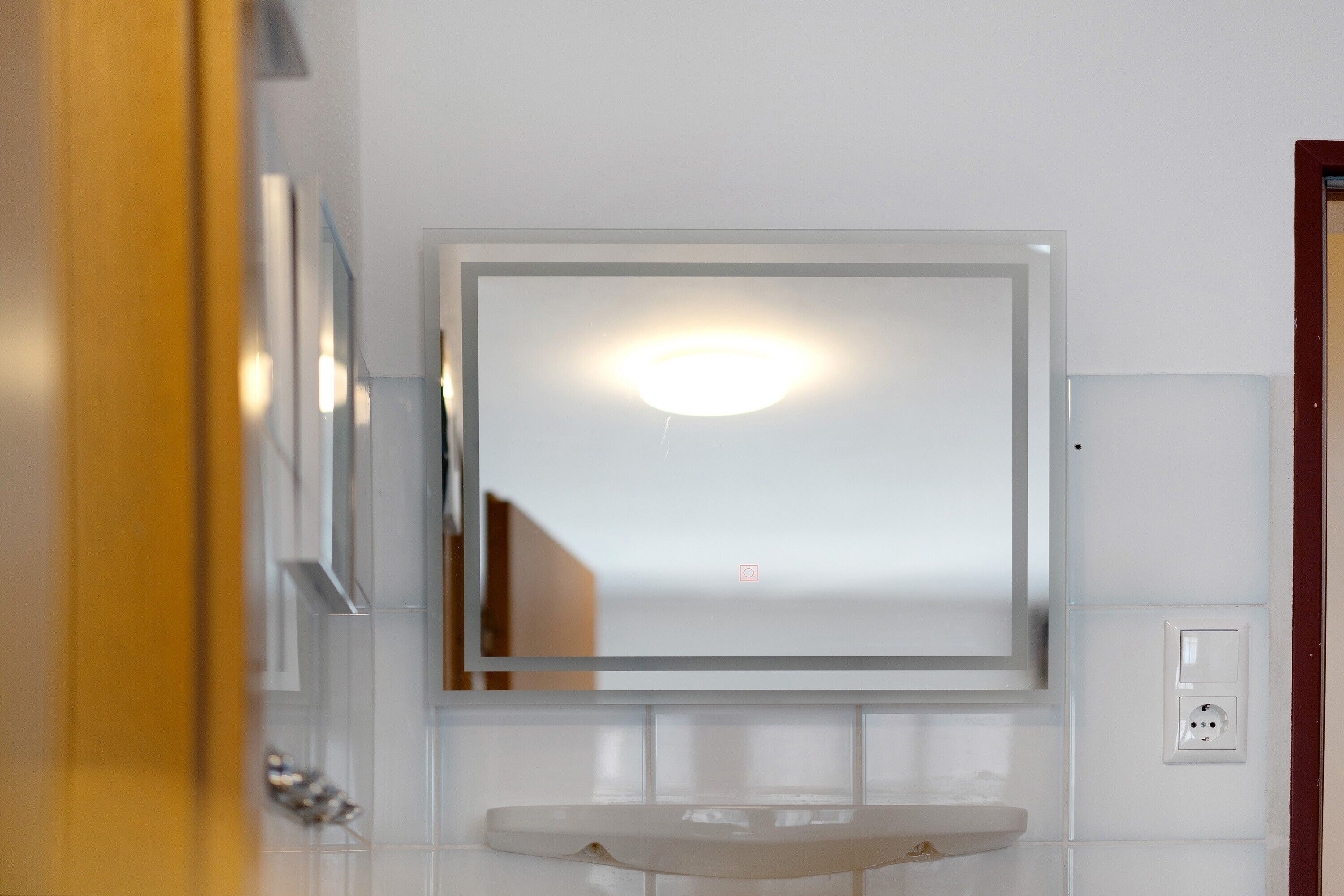 Une salle de bain avec un miroir, un lavabo et un luminaire.
