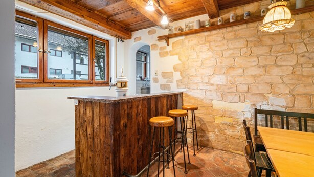 Een rustiek interieur met een houten bar, stenen muren en een uitzicht door een raam.