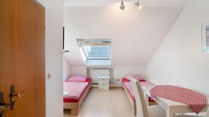 A bedroom with two beds, a desk, a window, and a radiator. - Knödelhof 'Room A', Twin Room – Guesthouse near Munich (Putzbrunn)