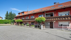 Un immeuble à plusieurs étages, doté d’une façade rouge, de balcons et d’une cour dallée.