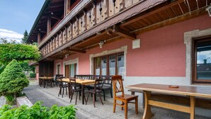 A building with a balcony, wooden furniture, and a small tree. - Knödelhof 'Apartment 8' – Guesthouse near Munich & Trade Fair (Putzbrunn)
