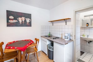 Une cuisine de taille réduite comprenant une table à manger, des chaises, une machine à café et un évier.