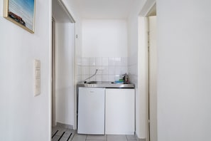 Une cuisine de taille réduite équipée d’un réfrigérateur, d’un évier et d’un plan de travail.