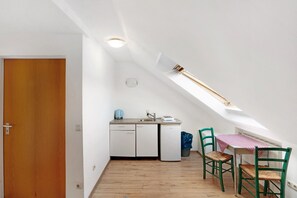 Une petite cuisine avec un puits de lumière, une table à manger avec des chaises et une porte en bois.