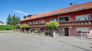 Ein mehrstöckiges Gebäude mit roter Fassade, Balkonen und einem gepflasterten Innenhof.