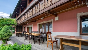 Ein Gebäude mit Balkon, Holzmöbeln und einem kleinen Baum.