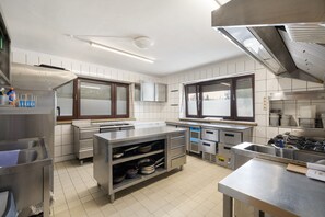 A modern kitchen with stainless steel appliances, a central island, and a window with blinds.