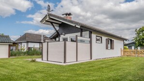 A modern house with a sloped roof, a fenced backyard, and a satellite dish. - Apartment 'Drybarg' with Private Terrace, Private Garden and Wi-Fi (Simonsberg)