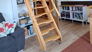 A wooden staircase in a room with a bookshelf, a sofa, and a door.
