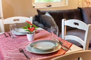 Une table à manger, avec des assiettes, des couverts et des verres, dressée sur une nappe rouge.