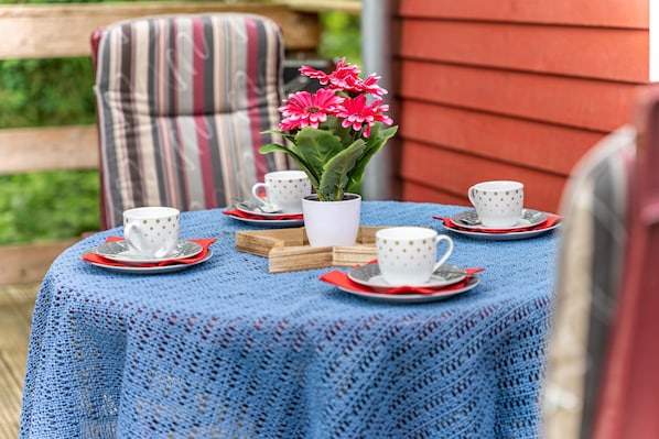 Une table avec des tasses et des soucoupes blanches, une plante en pot et une chaise à rayures.