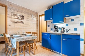 A kitchen with blue cabinets, a dining table set with plates and glasses, and a coffee maker.