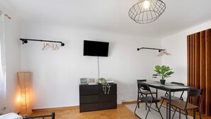 A bedroom with a bed, a dresser, a TV, a desk with chairs, and a potted plant. - M B Homes Nürtingen with Wi-Fi (Nürtingen)