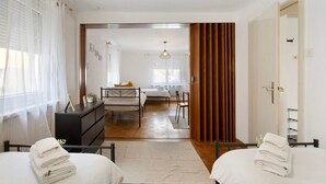 A hotel room with two beds, a desk, a chair, a dresser, and a view of the adjacent room. - M B Homes Nürtingen with Wi-Fi (Nürtingen)