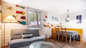 A cozy room with a sofa, dining table, and a wall decorated with fish.