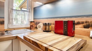 Une cuisine avec un plan de travail en bois, un appareil électroménager rouge et une fenêtre donnant sur la plage.