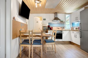 Une cuisine moderne avec des meubles en bois, un téléviseur à écran plat et un coin repas comprenant des chaises et une table.