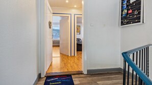 A hallway with a wooden floor, a blue and white door, and a welcome mat.