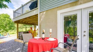 Ein Essbereich im Freien mit rotem Tischlaken, einer Weinflasche und Kerzen.