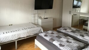 A bedroom with two beds, a TV, a mirror, and a wardrobe. - Apartment 'Fewo Eberau' with Shared Garden and Wi-Fi (Ebrach)