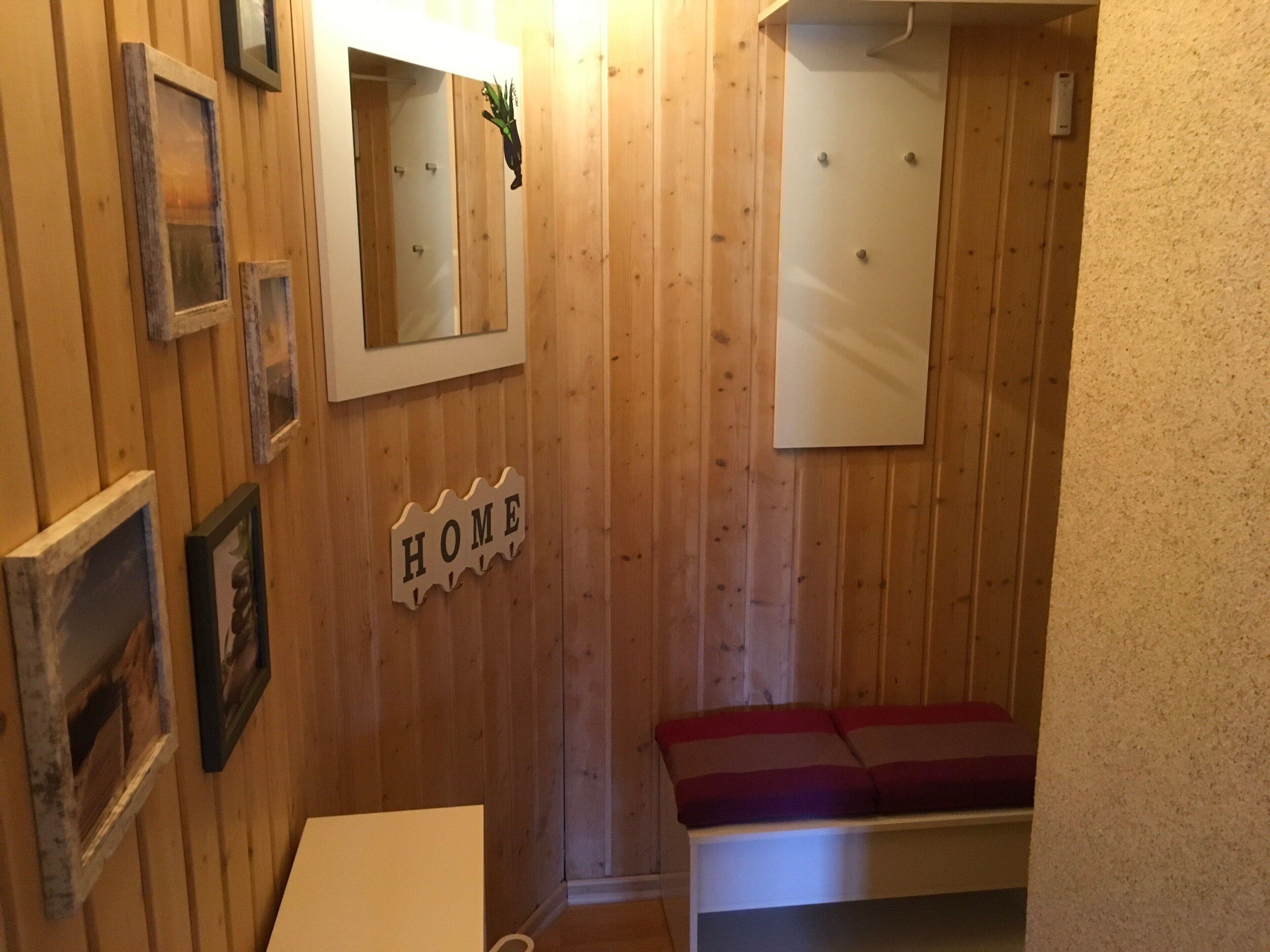 Ein Holzinnenraum mit einer Bank, einem Spiegel und einem Schild mit der Aufschrift 'HOME'.