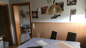 A dining area with a table set for four, a clock on the wall, and various coffee-themed decorations. - Apartment 'Fewo Eberau' with Shared Garden and Wi-Fi (Ebrach)
