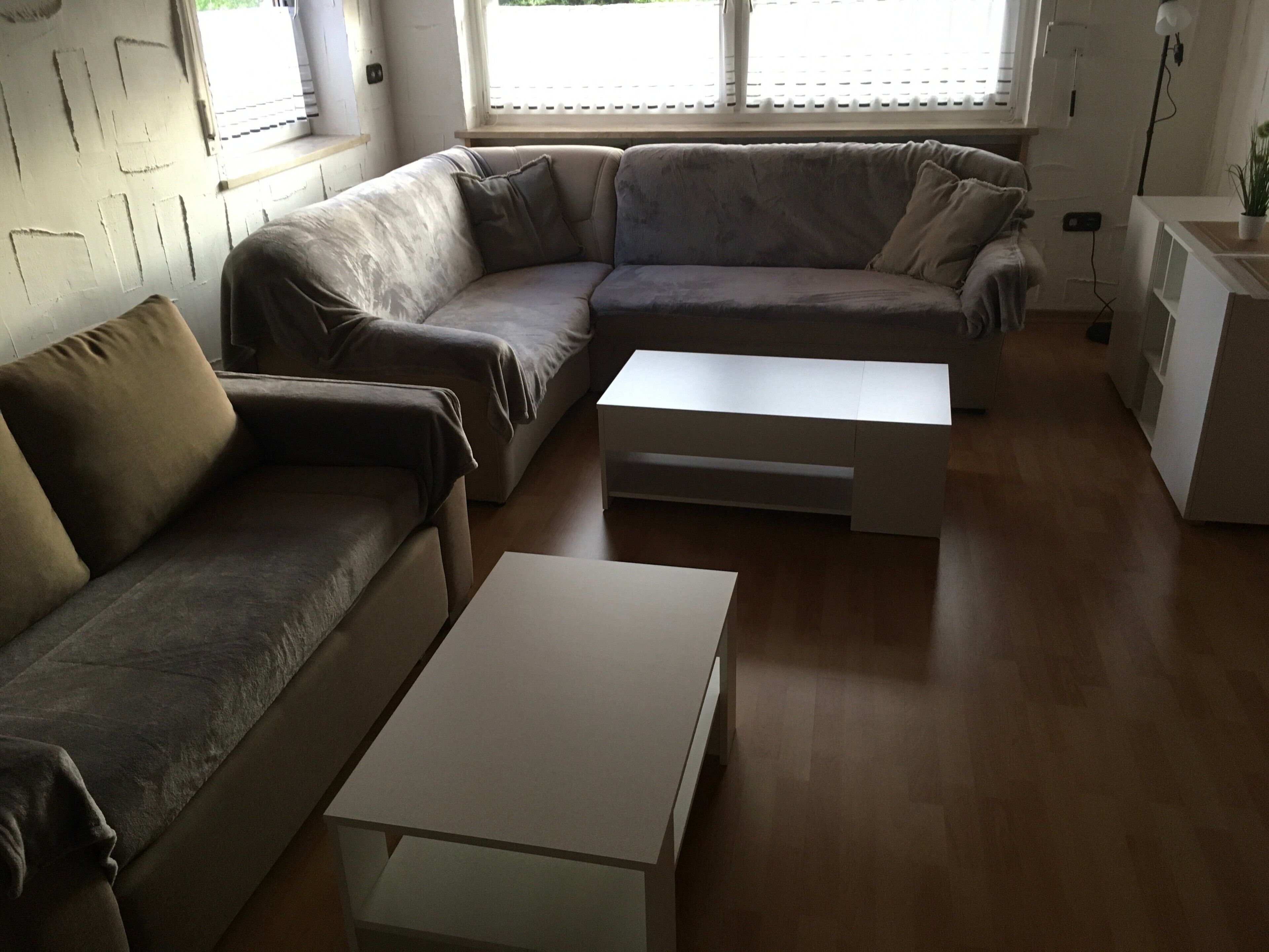 A living room with a sectional sofa, a coffee table, and a small white cabinet.