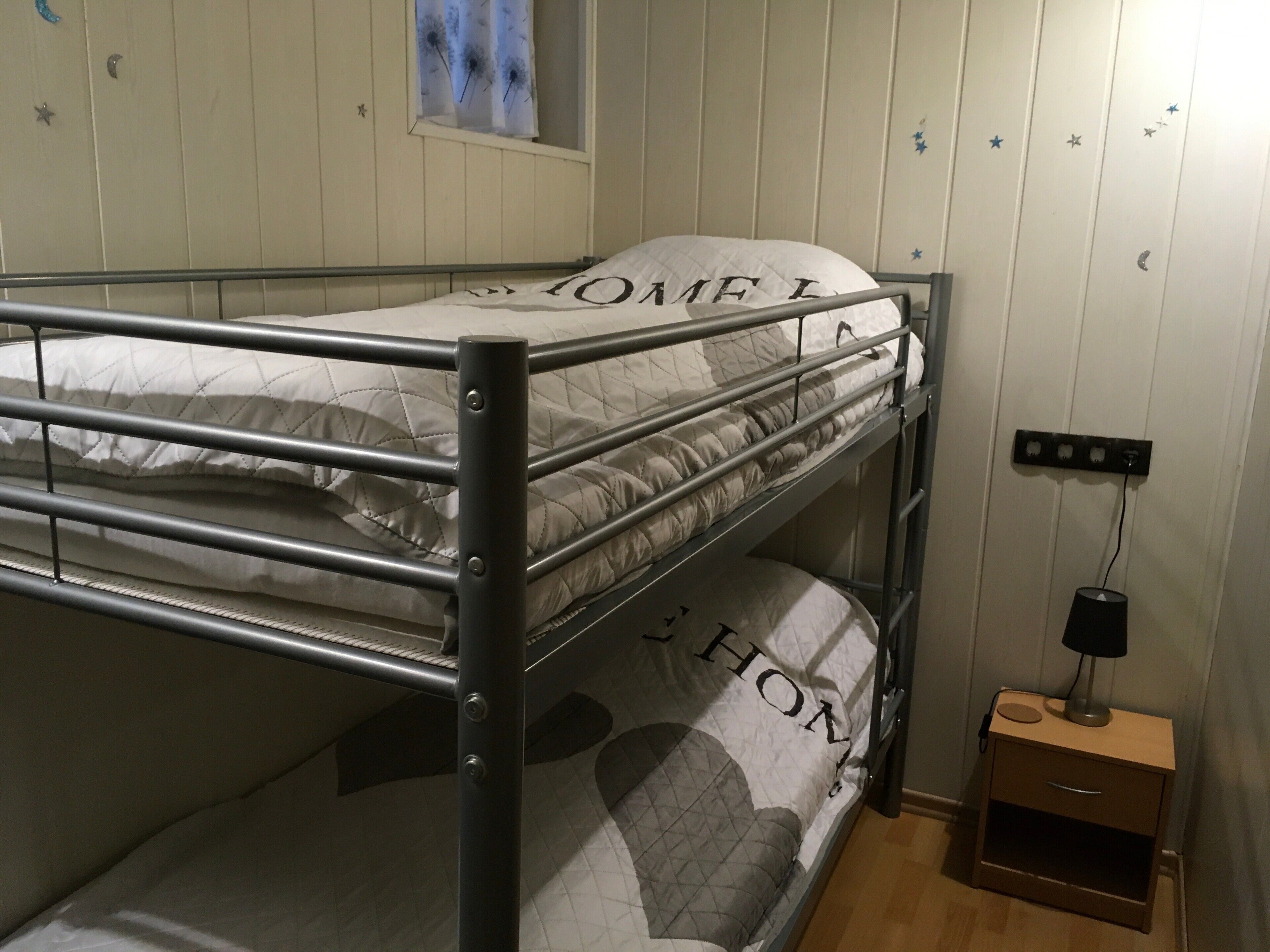 Un letto a castello con una finestra sopra e un comodino con una lampada.
