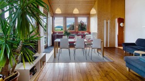 Un vaste espace de vie comprenant une table à manger, des chaises, un canapé et une grande plante en pot.