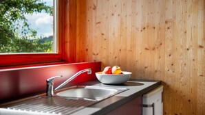 Une cuisine avec un mur en bois, une fenêtre, un évier et un saladier rempli de fruits.