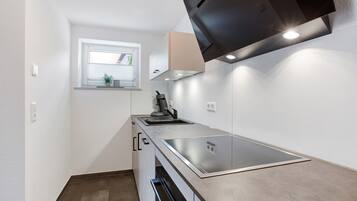 A compact kitchen with a built-in stove, a window, and a black range hood.