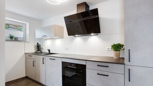 Une cuisine moderne dotée d’un four encastré, d’un four à micro-ondes et d’une grande hotte noire.